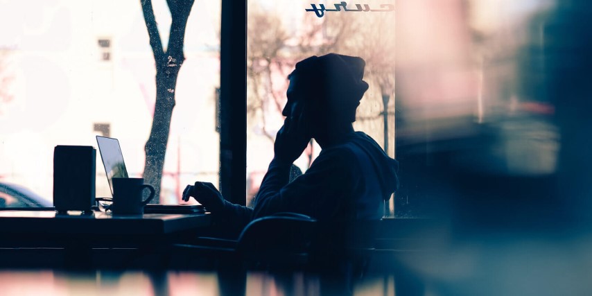 Unidentifyable young man in a coffee shop using WiFi