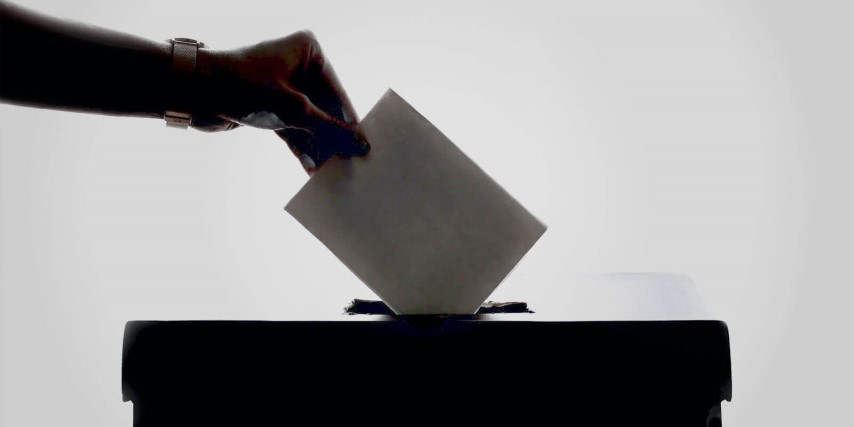 Hand placing vote in a ballot box in the dark